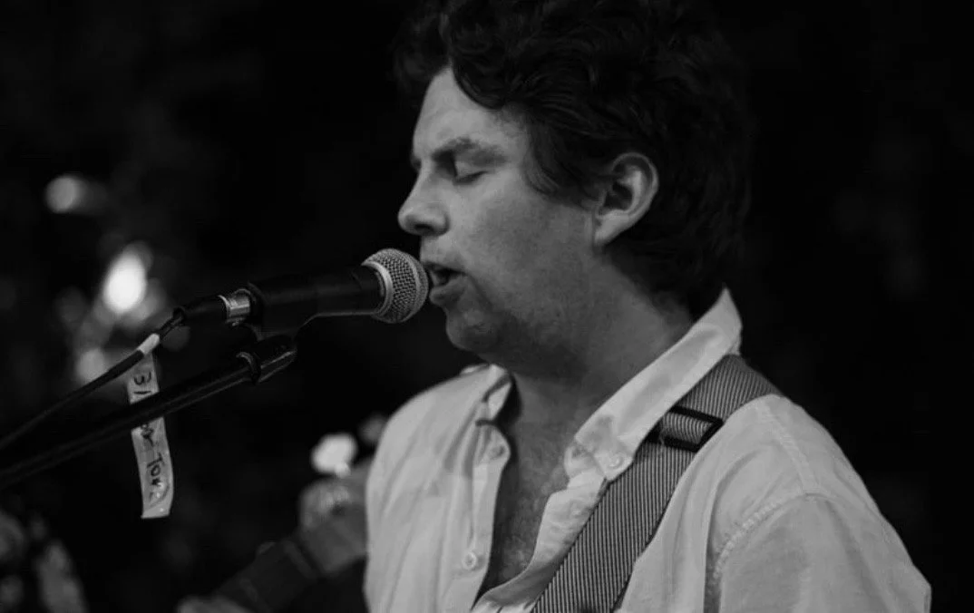 Black and white portrait of Matt Tuley singing into a microphone